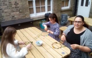 Children making floral crowns fit for a Rose Queen from artificial flowers on Saturday.